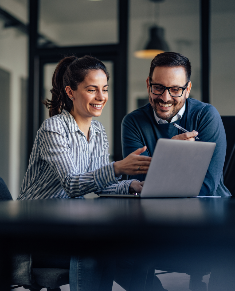 two business professionals at desk looking at laptop