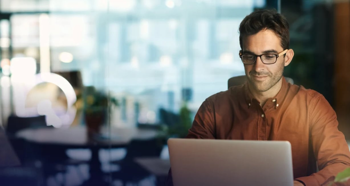 A professional using a laptop to manage AI security and Identity Security Posture Management (ISPM) for non-human identities. - Saviynt