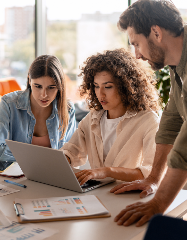 office workers at desk gathered around laptop