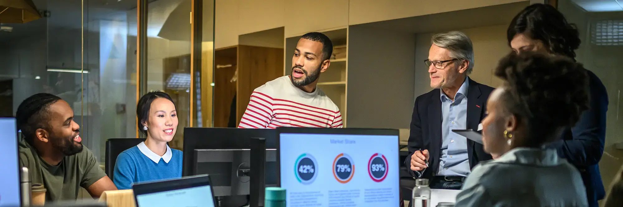 Diverse business professionals collaborating around a display in a modern office meeting.