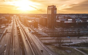 A high-angle view of the modern Espoo, Finland skyline and highway infrastructure captured during a bright golden sunset. - Saviynt