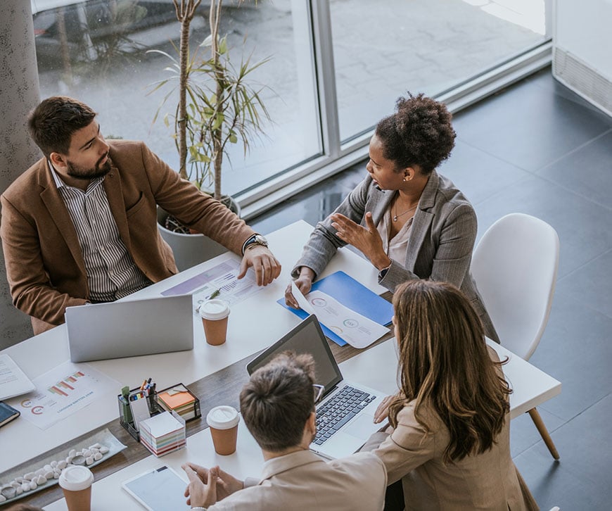 Ein Team eines Finanzdienstleisters, das gemeinsam am Konferenztisch daran arbeitet, die Prozesskonsistenz zu optimieren und die Einarbeitung neuer Mitarbeiter zu beschleunigen. – Saviynt
