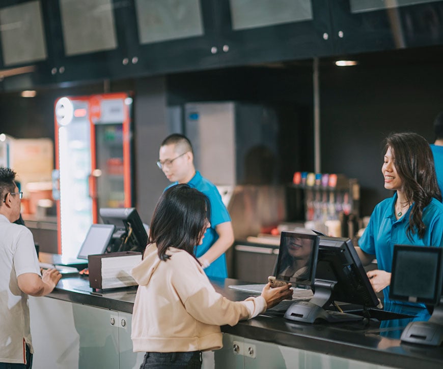 Restaurantmitarbeiter, die Kunden an einer modernen Kasse bedienen – ein Beispiel dafür, wie eine globale Restaurantkette ihre Systeme absichert, um die vollständige SOX-Konformität zu gewährleisten. – Saviynt