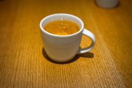 A white ceramic cup of iced coffee or tea on a wooden table.