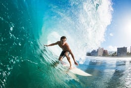 A surfer riding through a large turquoise barrel wave, illustrating the Ride the AI Wave theme.