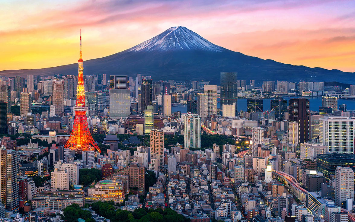 Vibrant Tokyo city skyline at sunset featuring the illuminated Tokyo Tower in the foreground and a snow-capped Mount Fuji rising in the background under a colorful sky. - Saviynt