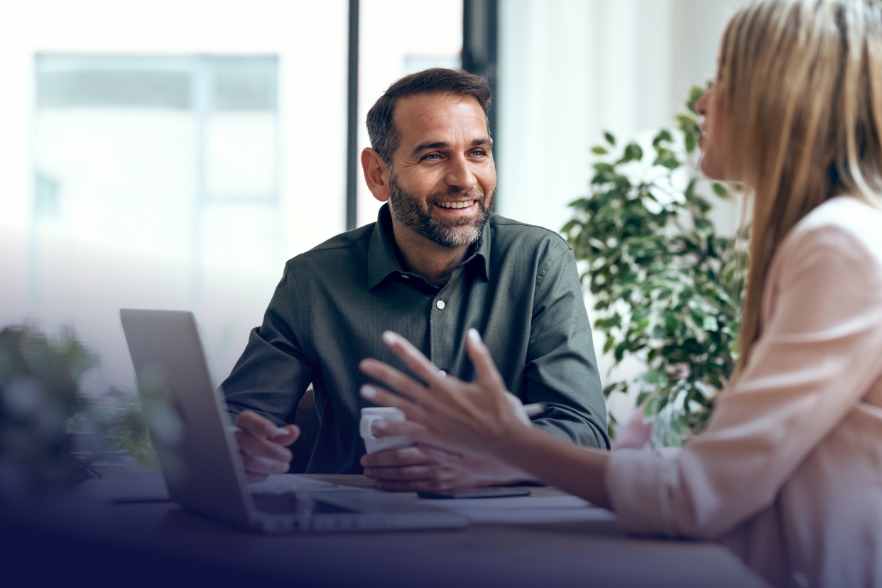 Coworker smiling at another coworker with laptop