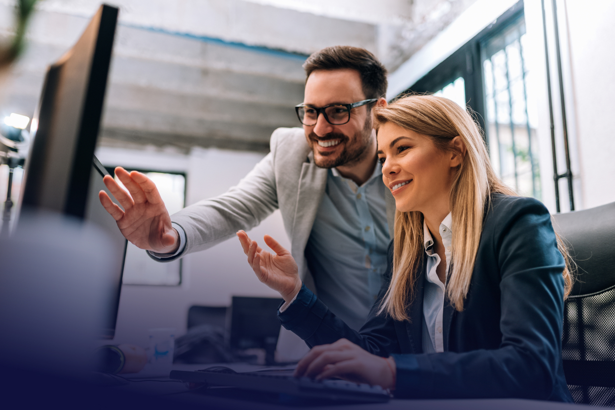 Two office co-workers smiling looking at computer together