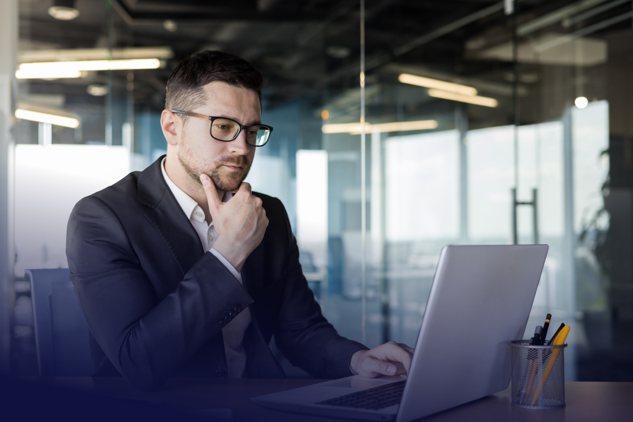 Office worker looking at laptop in contemplation