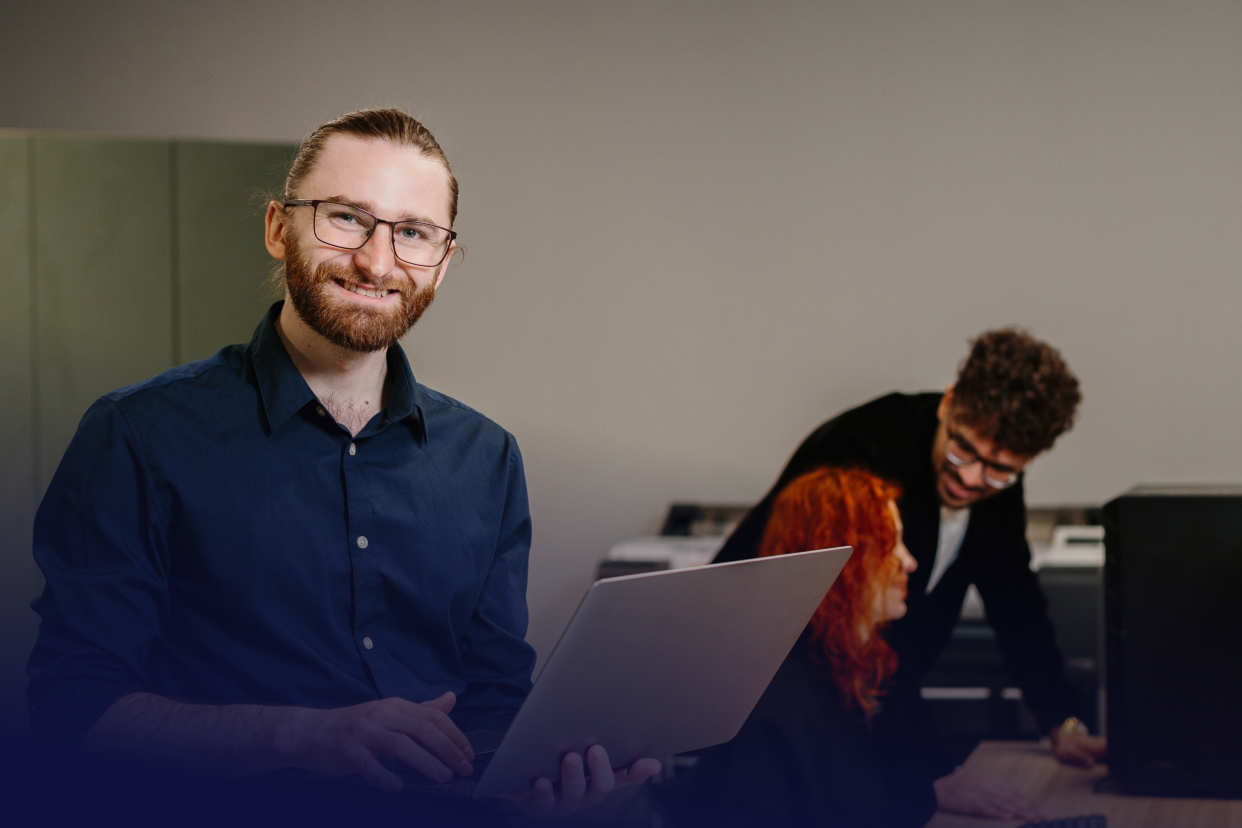 Office workers holding laptop and conversing
