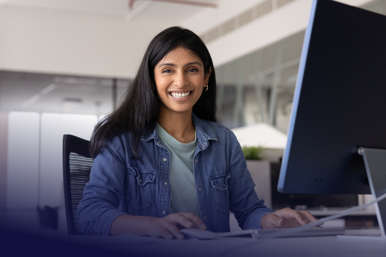 Office worker at computer and smiling