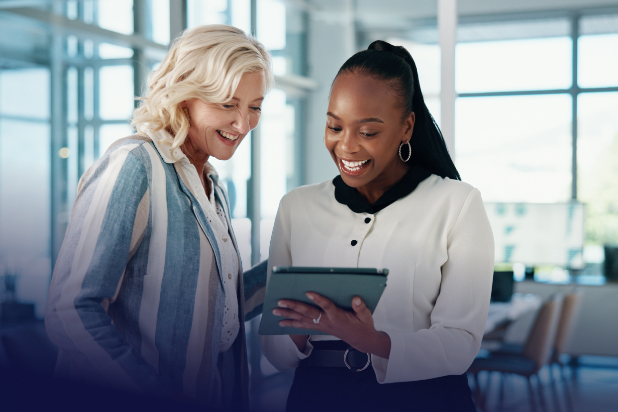 Two female coworkers looking at tablet in office