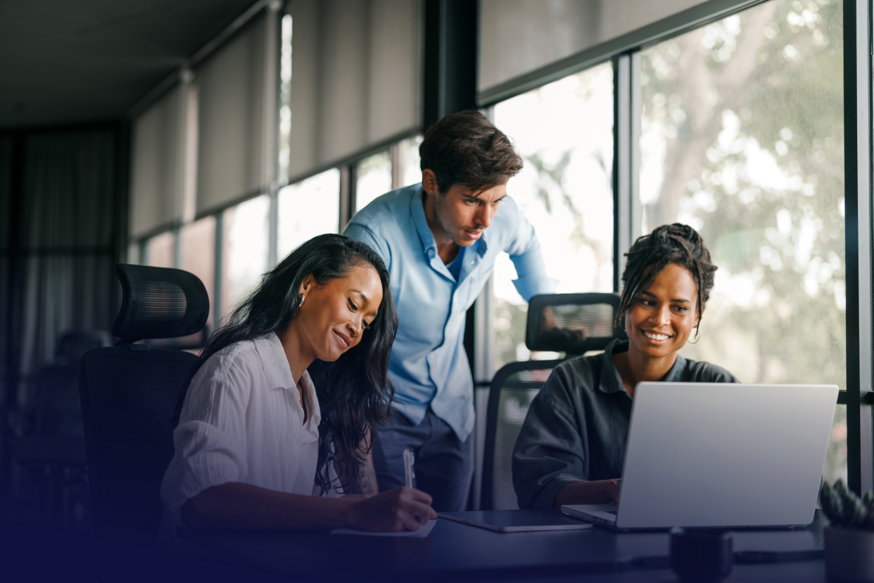 Three office workers looking at a laptop