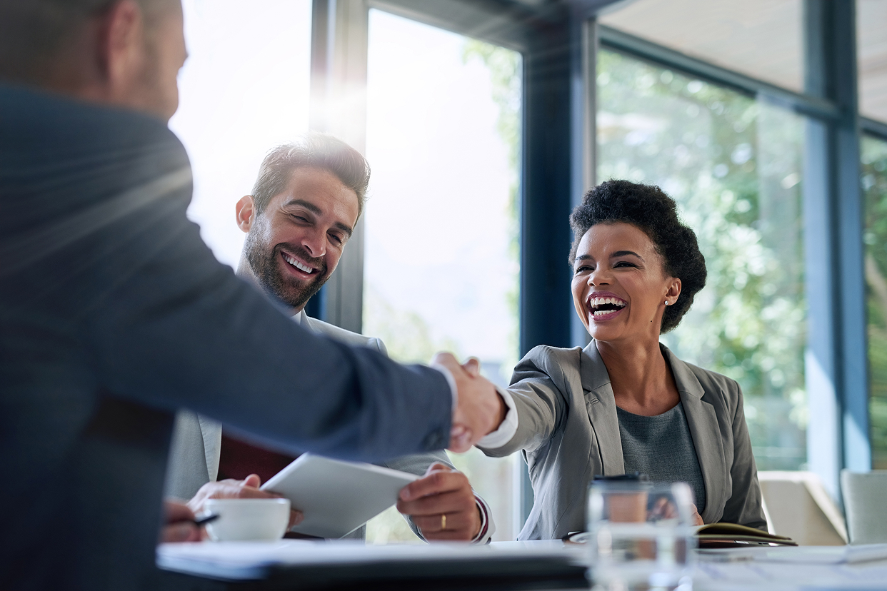 Professionals shaking hands at conference room table