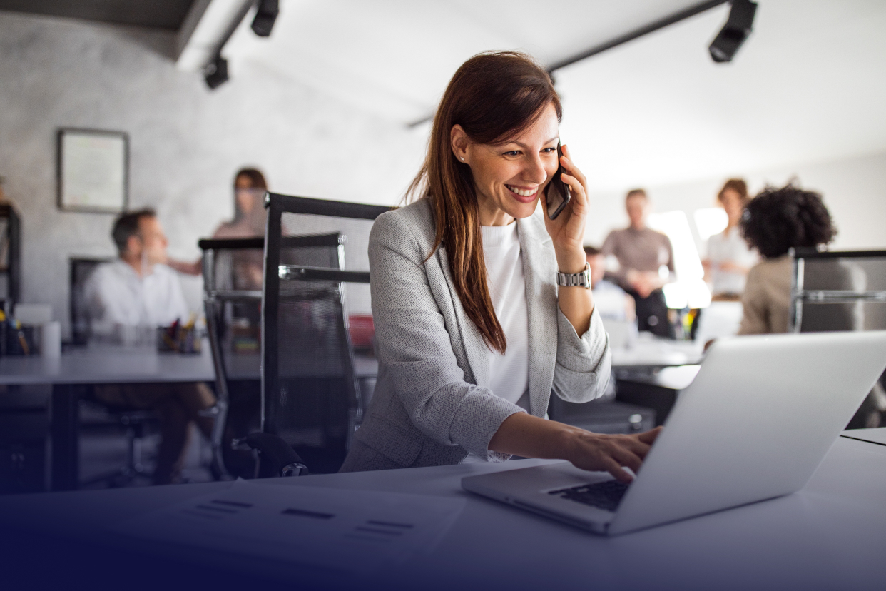 Officer worker on laptop and phone at desk