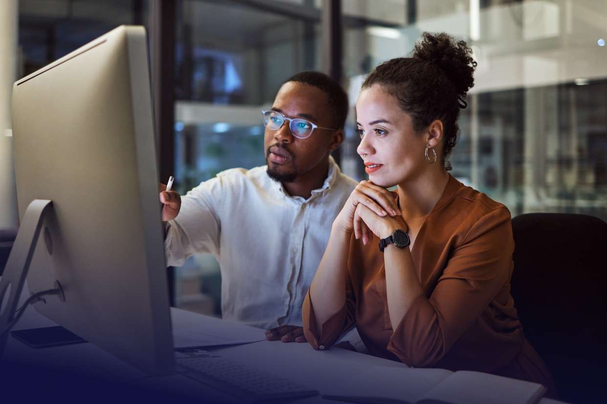 Two office workers looking at computer at desk